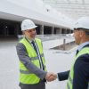 Waist up portrait of smiling mature businessman shaking hands with partner after investment deal at construction site, copy space